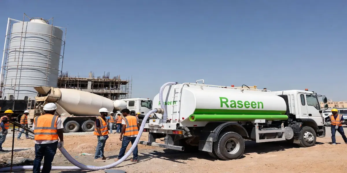 White and green water tanker supplying fresh water at construction site in Sharjah by Raseen